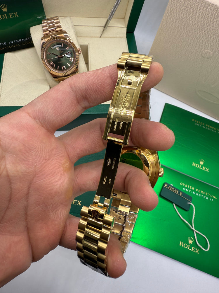 Relógio dourado com pulseira de metal e fecho, exibido na mão