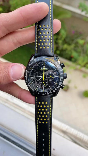 Relógio Omega com mostrador preto e pulseira de couro preta com furos e costura amarela