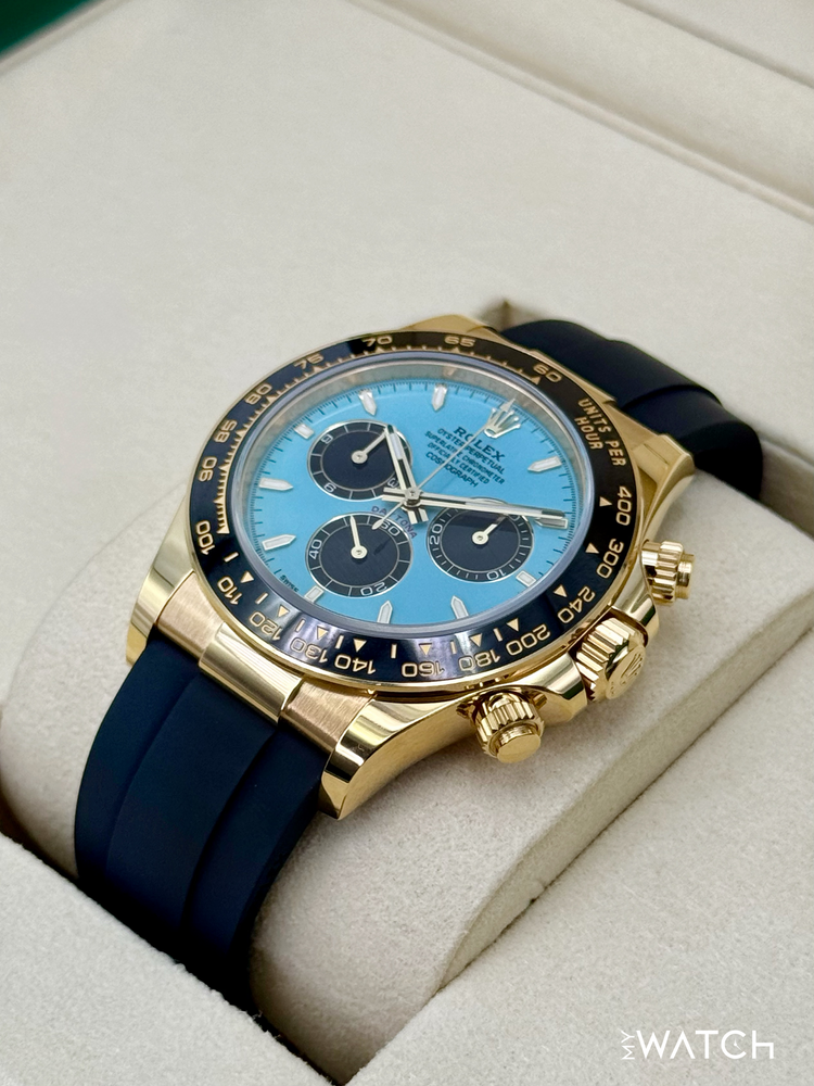 Relógio Rolex Daytona com caixa dourada e mostrador azul, pulseira azul em caixa acolchoada.