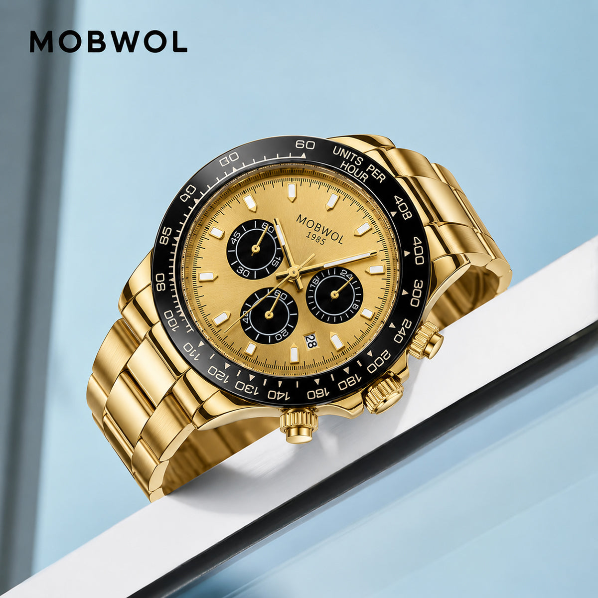 Relógio Movara® Pilotos dourado com cronógrafo, fundo bege e pulseira de metal.