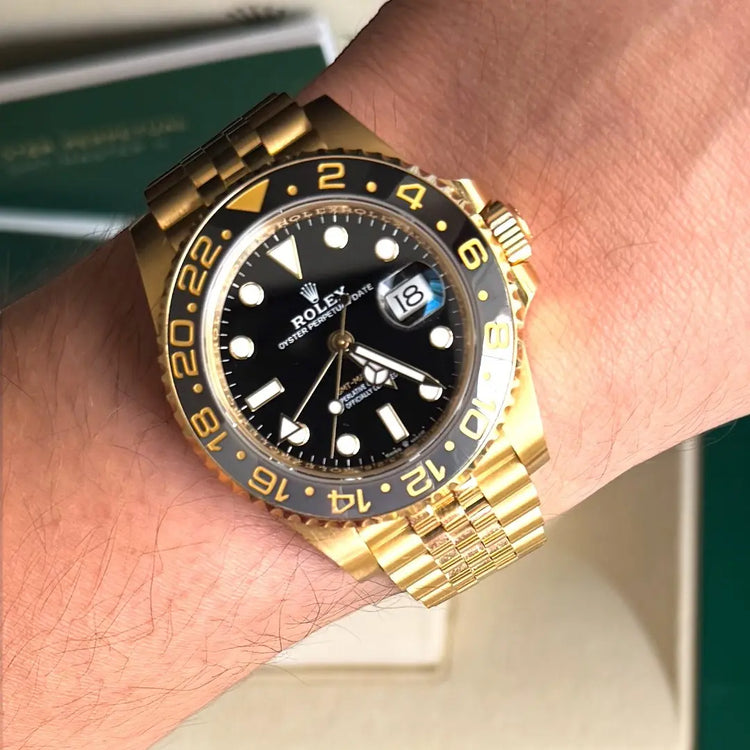 Relógio Rolex GMT Master II em ouro na mão, mostrador preto e pulseira dourada