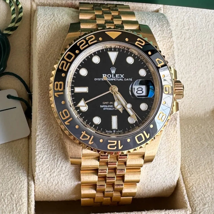 Relógio Rolex GMT Master II em ouro, mostrador preto com aro dourado e marcações azuis