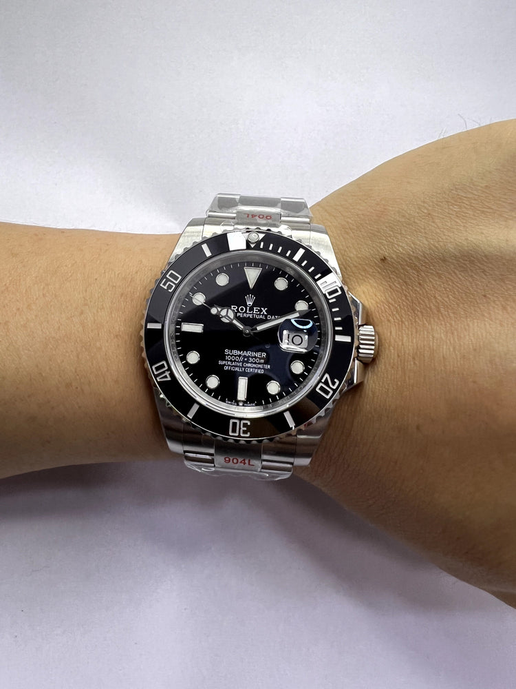 Relógio Rolex com mostrador preto e pulseira de aço no pulso