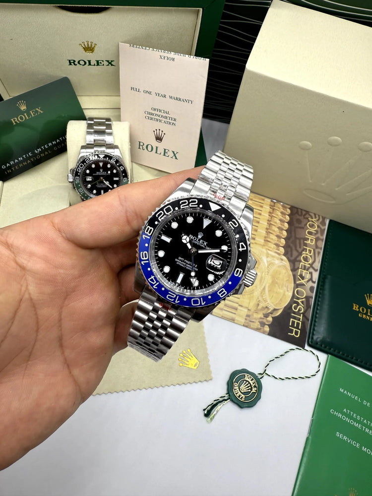 Relógio automático Rolex na mão, mostrador preto e moldura azul, pulseira de aço