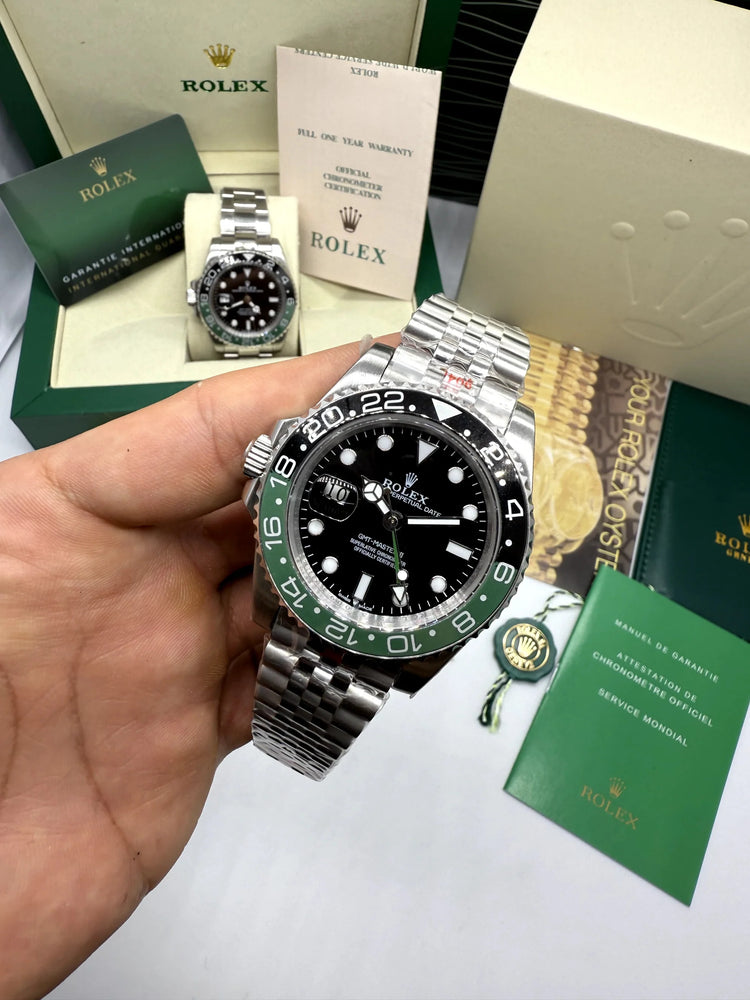 Relógio Rolex GMT Master II na mão, mostrador preto, aro verde e pulseira de aço
