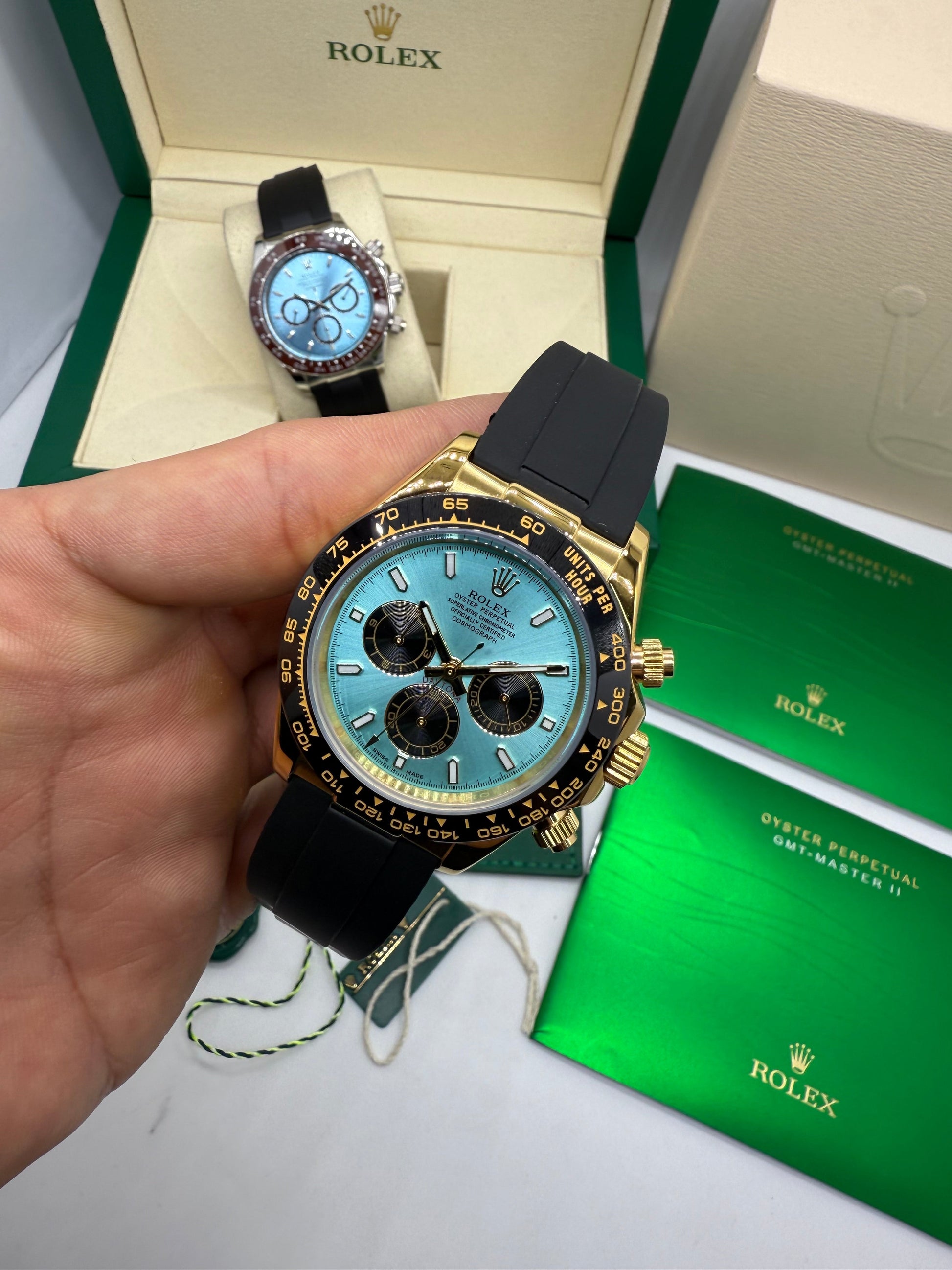 Relógio Rolex Daytona com pulseira azul e mostrador azul, caixa dourada e botões laterais.