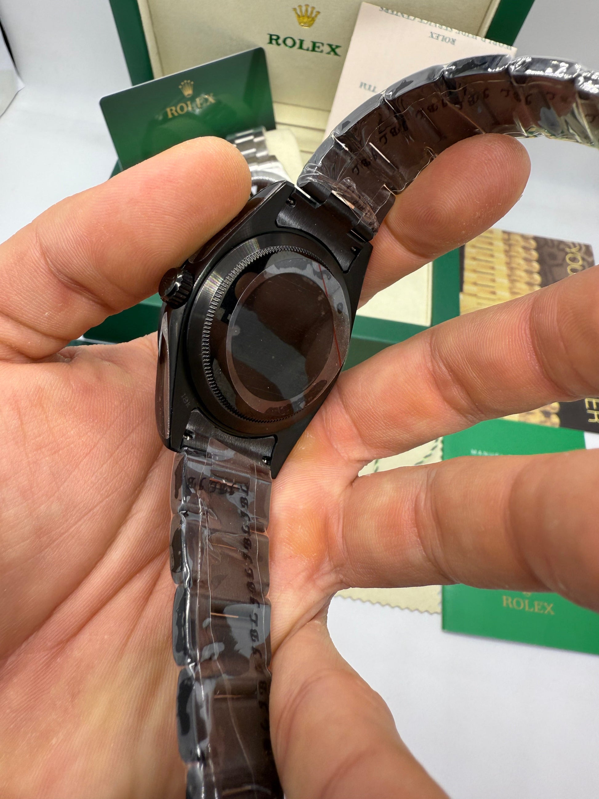 Relógio preto em close na mão, fundo da caixa e pulseira de aço