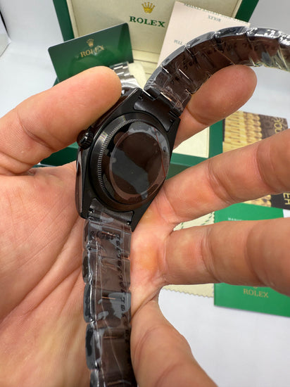 Relógio preto em close na mão, fundo da caixa e pulseira de aço