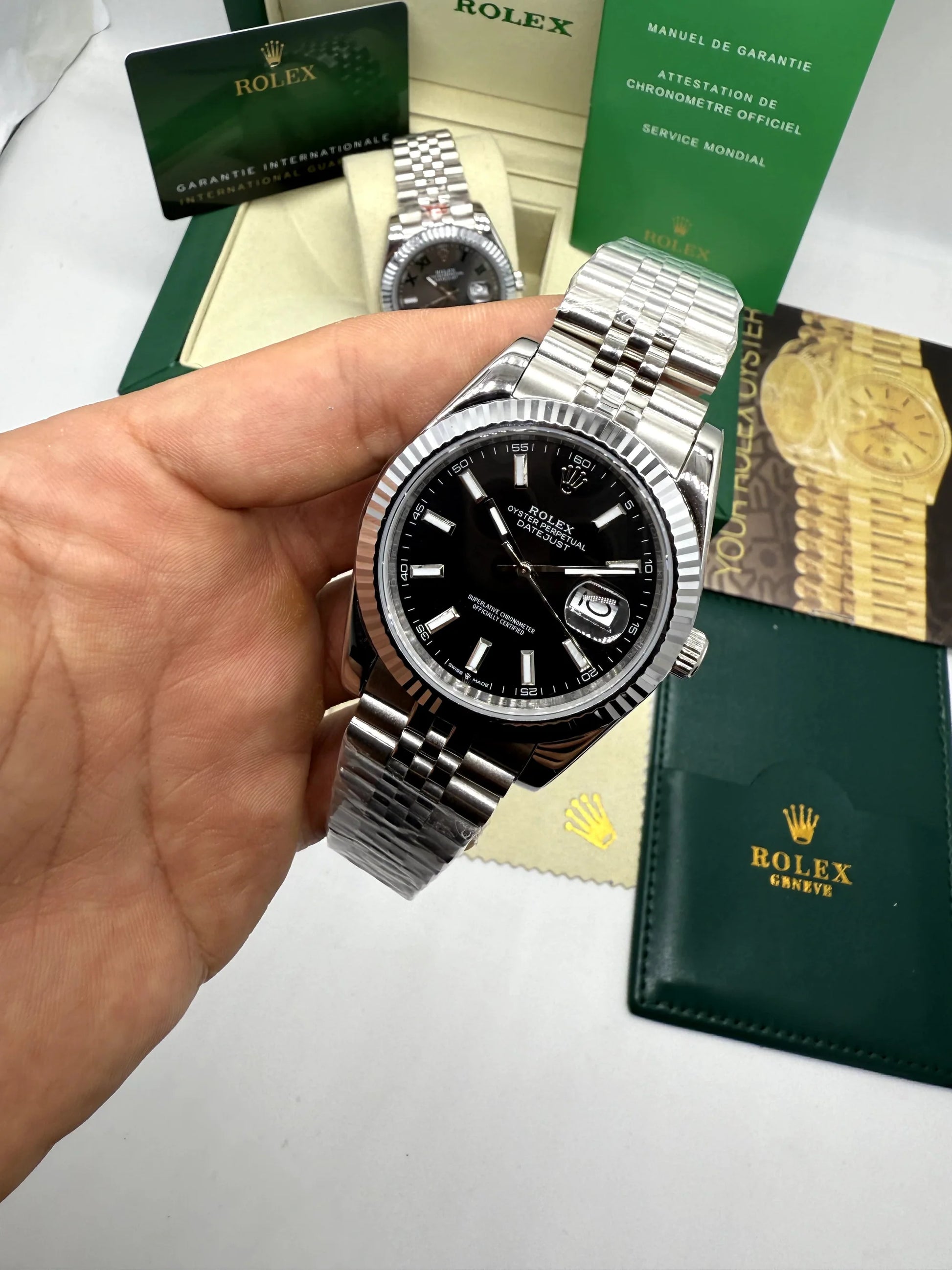 Relógio Rolex Datejust com mostrador preto e pulseira de aço, segurado na mão