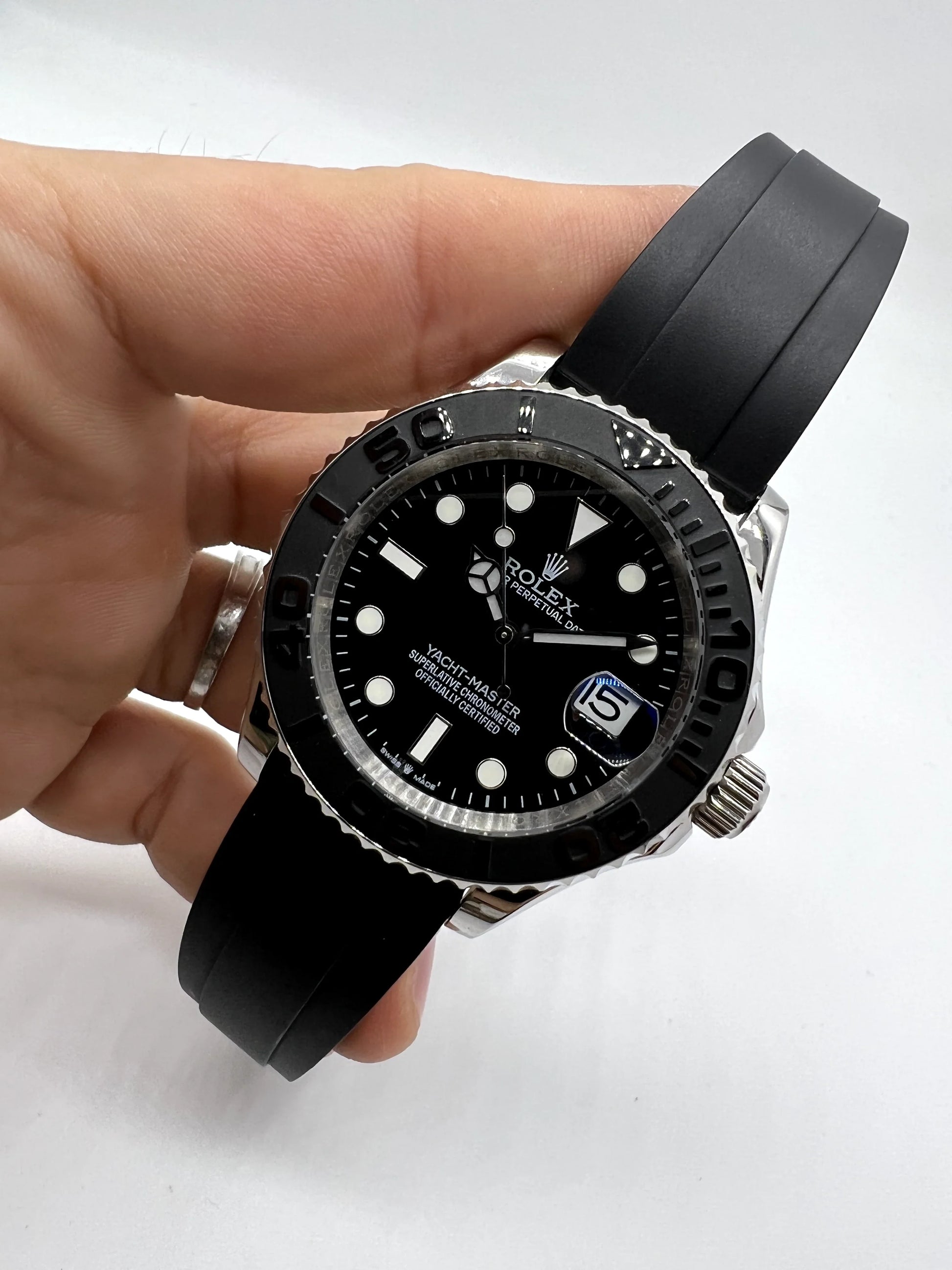 Relógio Rolex automático com mostrador preto e pulseira de borracha preta no punho.