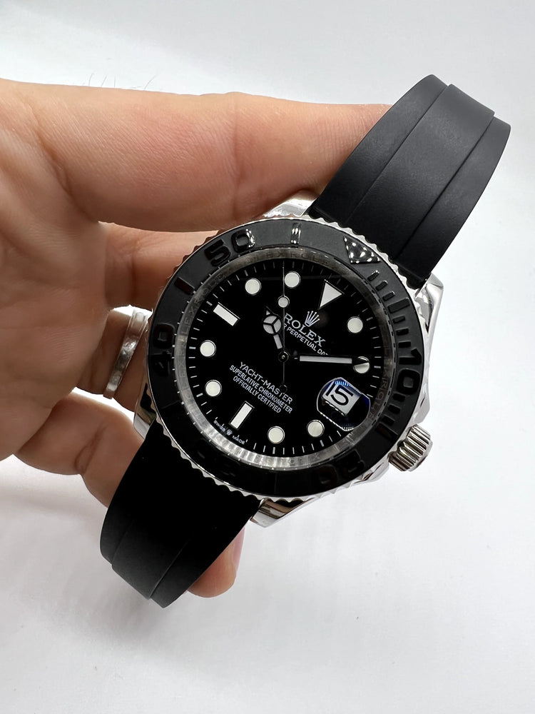 Relógio Rolex automático com mostrador preto e pulseira de borracha preta no punho.