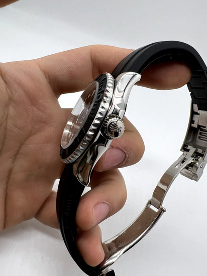 Relógio Rolex automático com caixa metálica e coroa lateral, pulseira de borracha preta.