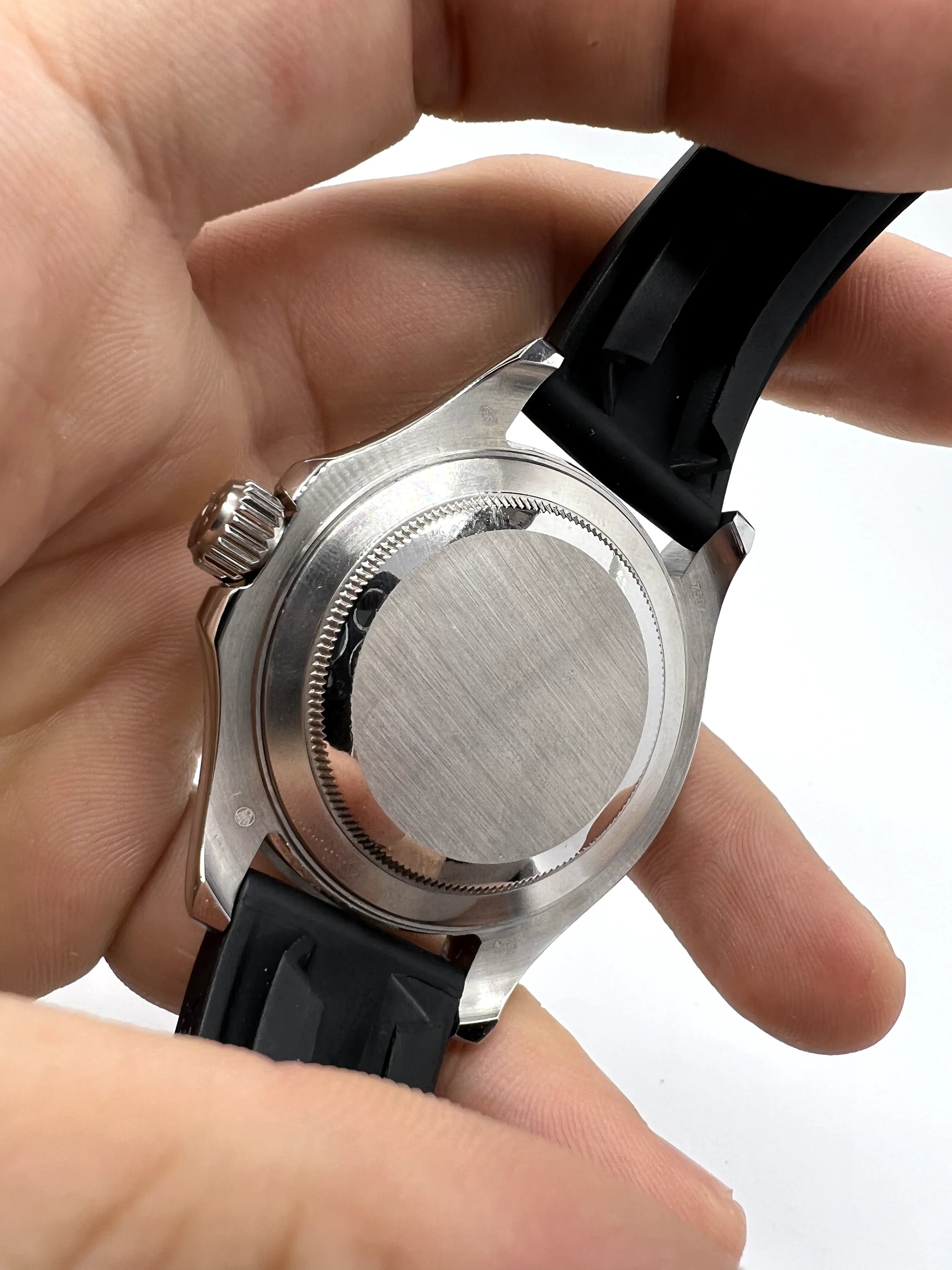 Tampa traseira em metal de relógio Rolex automático com pulseira de borracha preta.