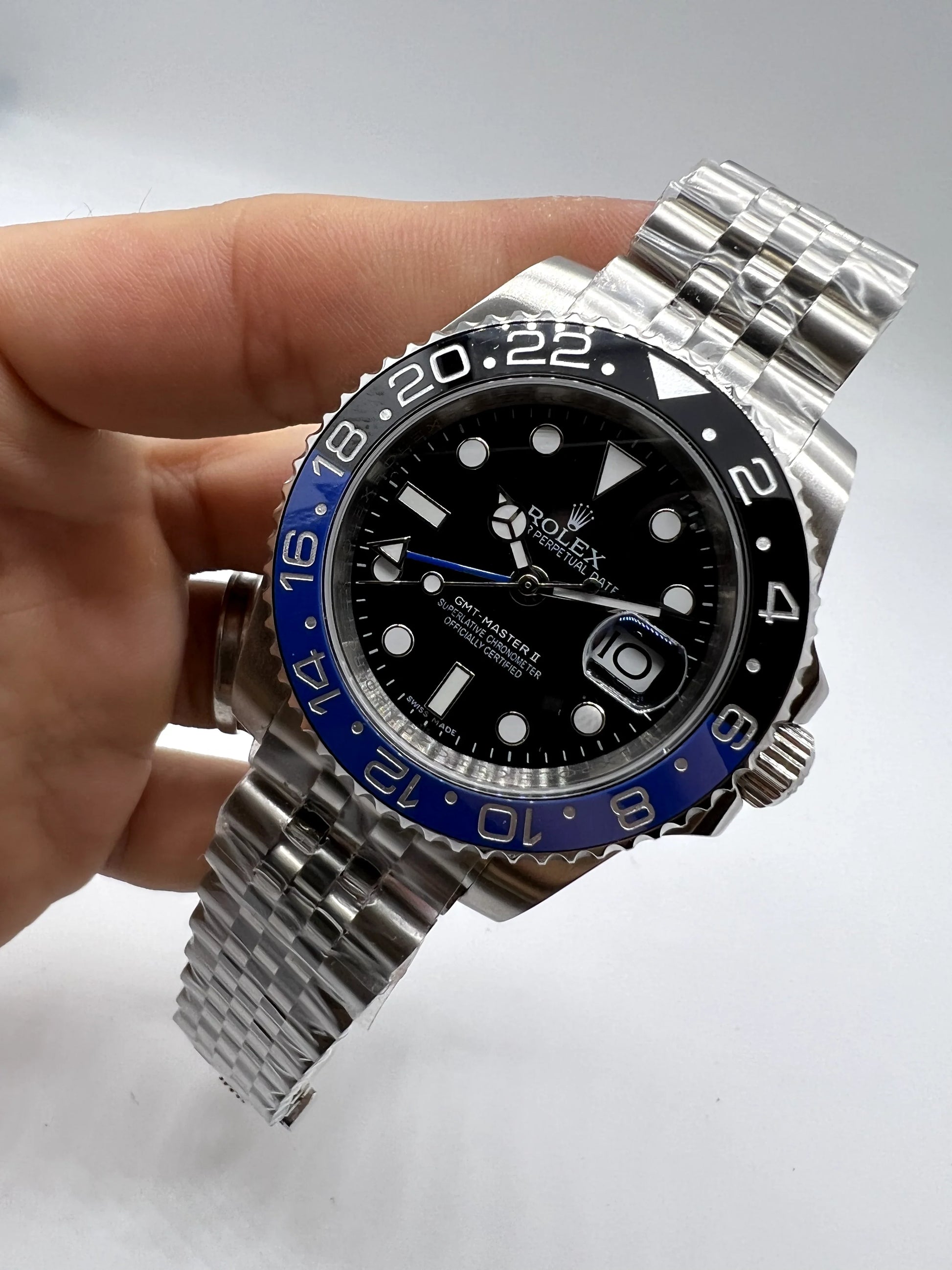 Relógio automático Rolex com mostrador preto e moldura azul, visto em ângulo