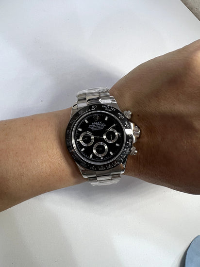 Relógio automático com mostrador preto e cronógrafo no pulso, pulseira de aço prateado