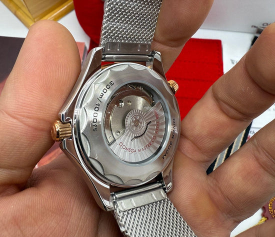 Relógio Omega com tampa traseira de aço e pulseira metálica na mão