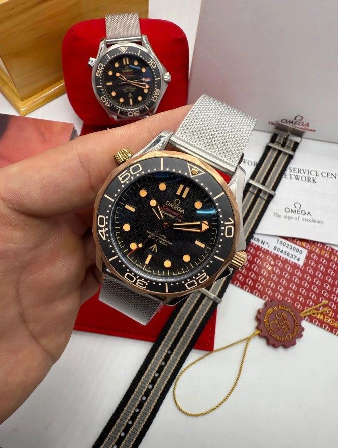 Relógio Seamaster Diver 300 com bezel dourada, mostrador preto e pulseira metálica