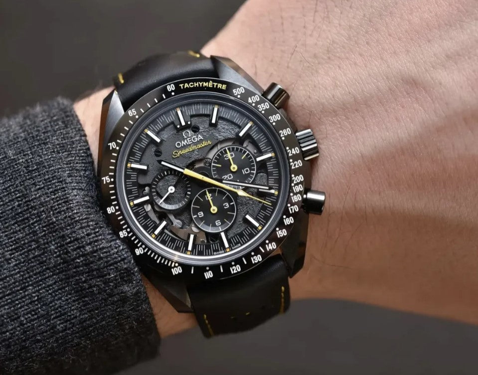 Relógio Omega Speedmaster com mostrador preto e detalhes amarelos, pulseira de couro preta