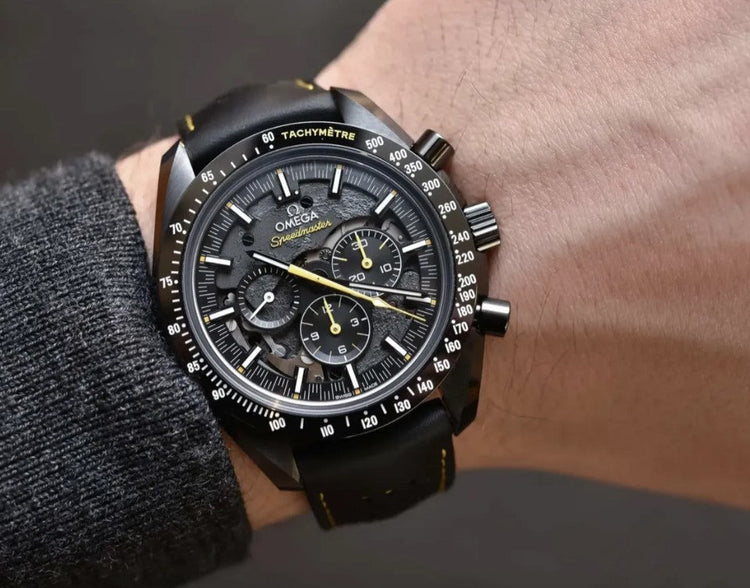 Relógio Omega Speedmaster com mostrador preto e detalhes amarelos, pulseira de couro preta