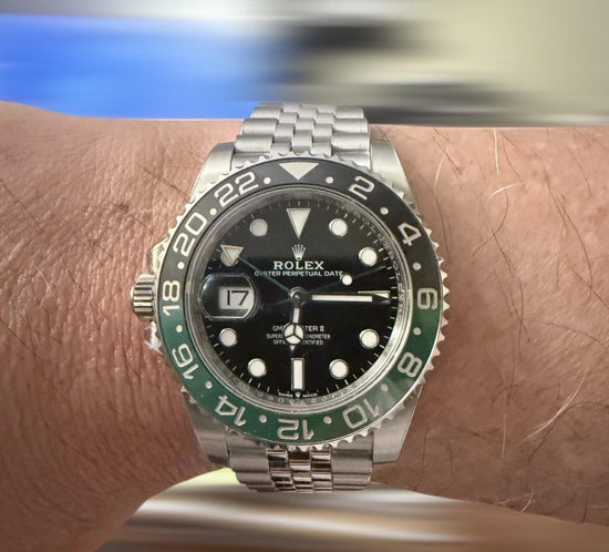 Relógio Rolex GMT Master II no pulso, mostrador preto e aro verde em aço