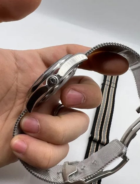 Relógio Omega em vista lateral com coroa em aço e pulseira de malha metálica