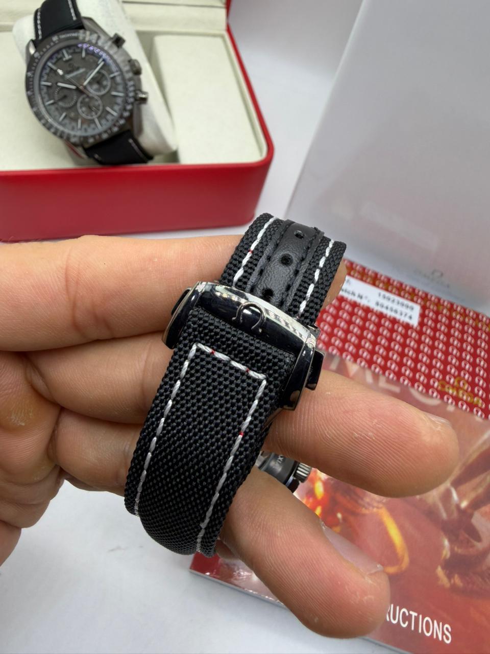 Fecho do relógio Omega Speedmaster com pulseira preta de tecido e costura clara