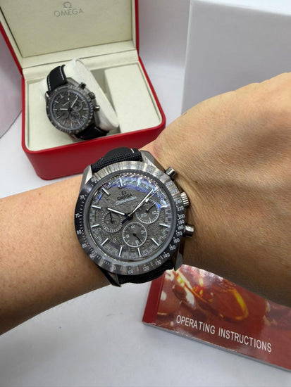 Relógio Omega Speedmaster no pulso, mostrador escuro e pulseira preta de tecido