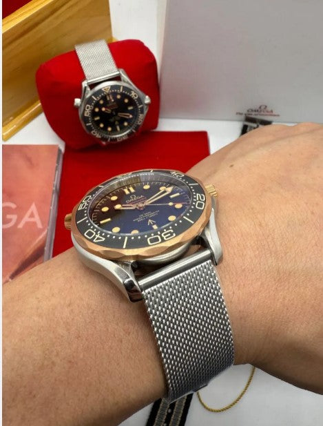 Relógio automático com mostrador preto, ponteiros e bezel dourada; pulseira de aço