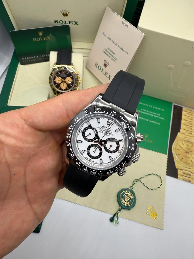 Relógio Rolex Daytona na mão, mostrado frontal branco e pulseira preta, lateral visível