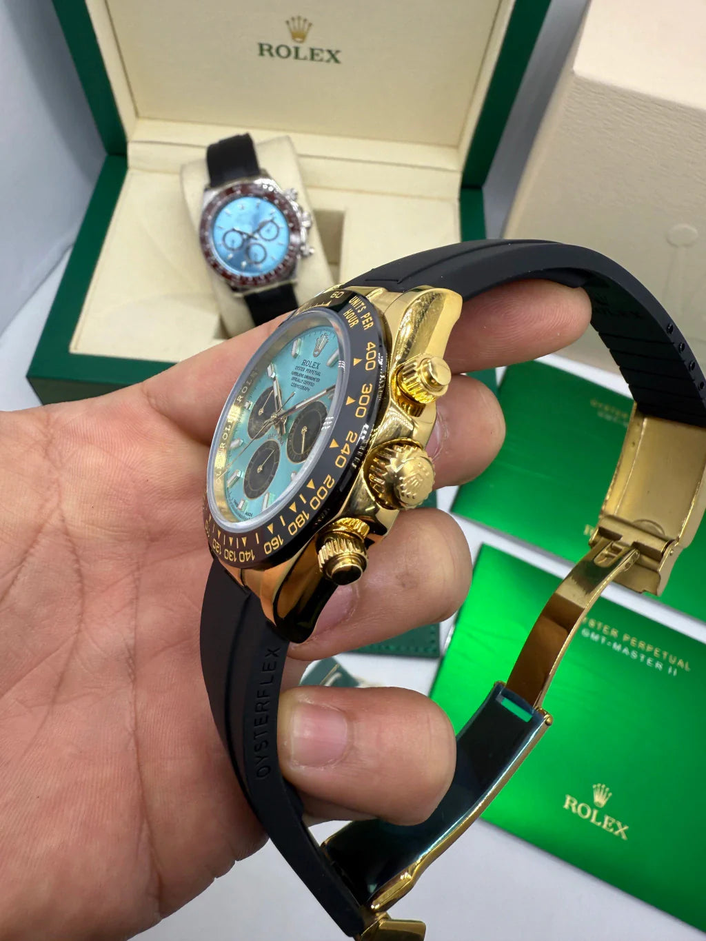 Relógio Rolex Daytona visto de lado, caixa dourada e pulseira azul com mostrador azul.