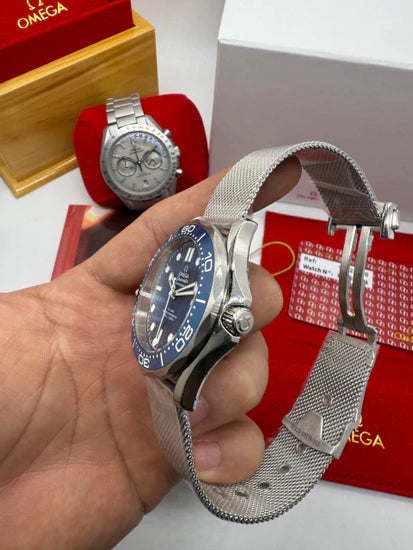 Relógio Omega Seamaster azul com caixa prateada e pulseira metálica, em mãos