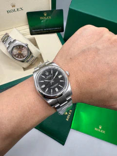 Relógio Rolex com mostrador preto na pulseira de aço, no pulso