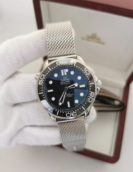 Relógio Omega com mostrador azul e bezel com marcações; pulseira de aço em malha