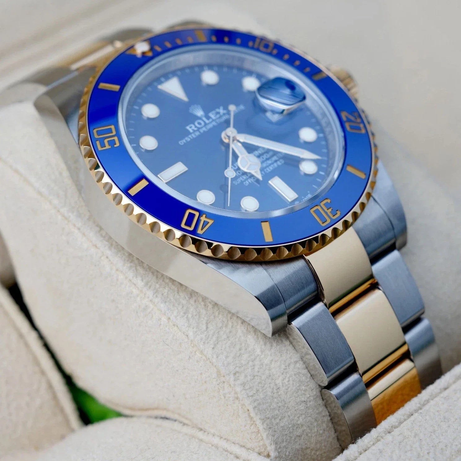 Relógio Rolex Submariner com luneta azul e pulseira bicolor aço e dourado, close.
