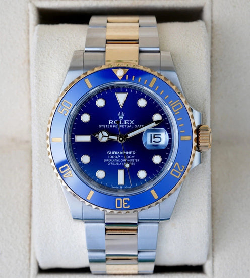 Relógio Rolex Submariner com mostrador azul e janela de data na pulseira bicolor.